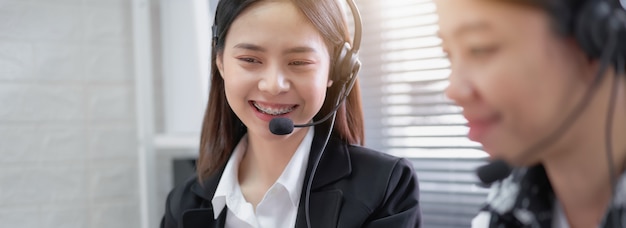 Consultor de mujer asiática sonriente con auriculares de micrófono del operador de teléfono de atención al cliente en el lugar de trabajo.