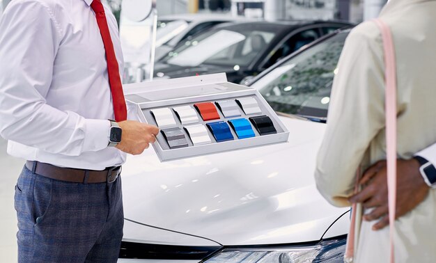 Consultor profesional caucásico confiado muestra la paleta de colores de los coches a los clientes