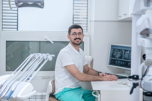 En el consultorio del dentista. Joven dentista en su oficina mirando ocupado