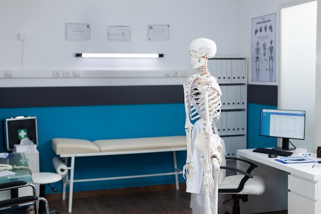 Consultorio médico vacío equipado con esqueleto de cuerpo humano utilizado como instrumento médico durante el examen de osteopatía. Habitación de hospital sin nadie que tenga estructura anatómica ósea. Vista de diapositiva