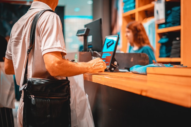 Foto consumidor adulto pagando con tarjeta de crédito en la tienda, sosteniendo una billetera
