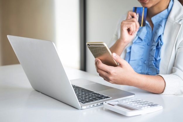 Consumidor joven con smartphone, tarjeta de crédito y portátil.