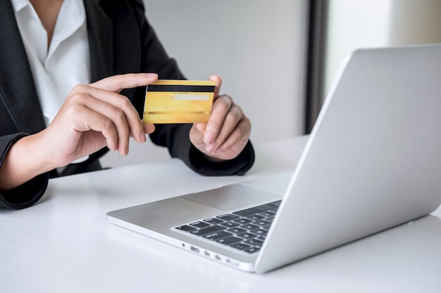 Consumidor de mujer de negocios con tarjeta de crédito y escribiendo en la computadora portátil para compras y pagos en línea, realice una compra en Internet, pago en línea, redes y compre tecnología de productos