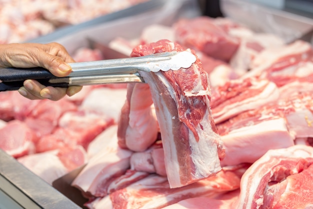 Consumidor seleccionando chuleta de cerdo fresca y limpia en supermercado