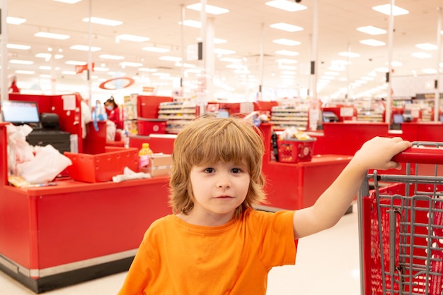 Consumismo de venda e conceito de pessoas menino feliz com comida no carrinho de compras na mercearia