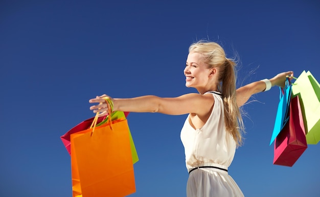 consumismo, venda e conceito de pessoas - mulher sorridente com sacola de compras levantando as mãos