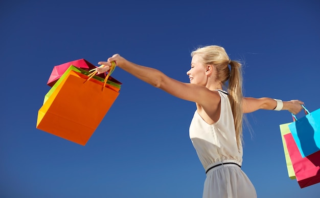 Foto consumismo, venda e conceito de pessoas - mulher sorridente com sacola de compras levantando as mãos