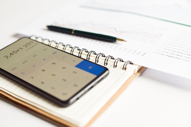 Foto contabilidade financeira com relatórios em papel e calculadora no smartphone