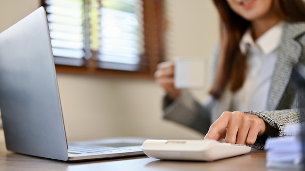 Contabilista asiática profissional usando calculadora para calcular e verificar seus dados financeiros