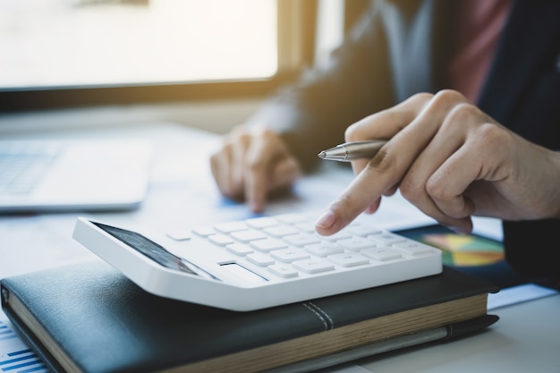 Contable de mujeres empresarias utilizan la calculadora y la computadora portátil para pagar impuestos en el escritorio blanco en la oficina de trabajo.