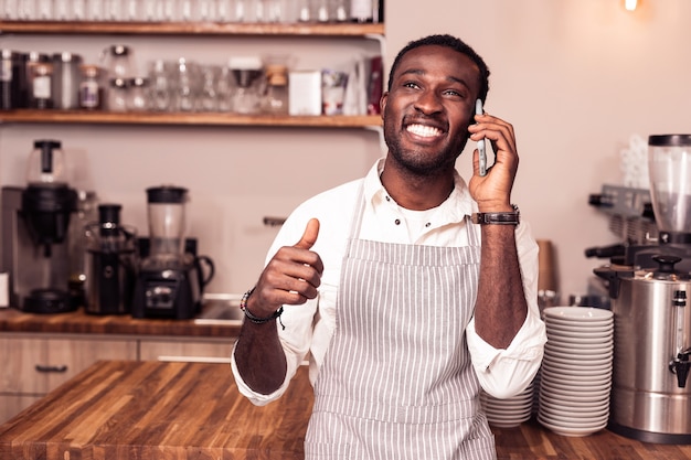 En contacto. Hombre feliz alegre sonriendo mientras tiene una conversación telefónica