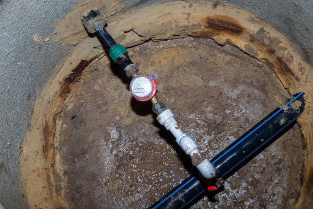 Contador de agua en un pozo subterráneo. Tubería para una casa de campo.