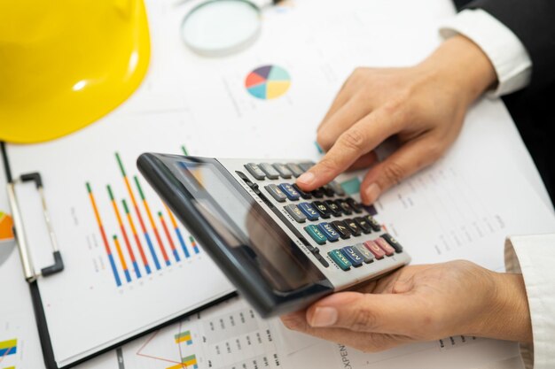 Foto contador asiático trabajando y analizando informes financieros contabilidad de proyectos con gráfico y calculadora en oficina moderna concepto de finanzas y negocios