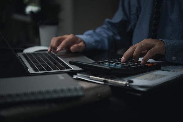 Foto contador de homem usando calculadora e laptop no escritóriofinanças e contabilidade analisando o conceito de investimento