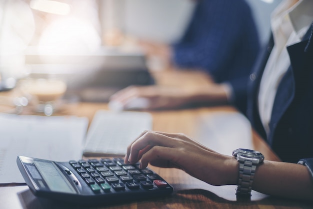 Contador de mulher trabalhando usando calculadora para calcular o relatório financeiro no local de trabalho