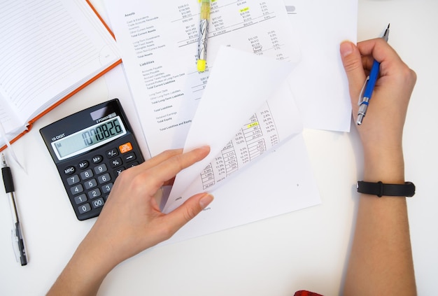 Contador opera con informes en mesa blanca con calculadora