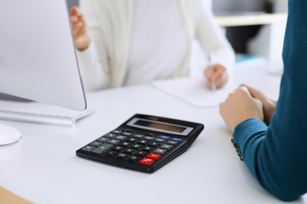 Contador revisando el estado financiero o contando por ingresos de la calculadora para el primer plano de las manos del formulario de impuestos