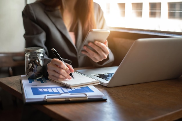 Contador trabalhando na mesa no escritório usando smartphone e laptop para calcular finanças e contabilidade do conceito de orçamento