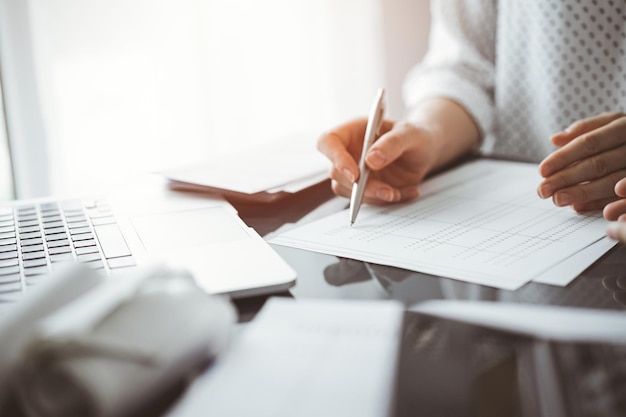Contadora usando uma calculadora e um computador portátil enquanto conta e discute impostos com um cliente Conceitos de auditoria e finanças de negócios