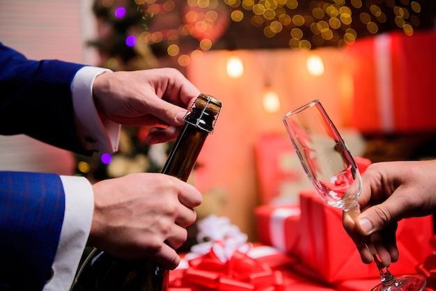 Contagem regressiva de ano novo. Mãos abrindo a garrafa de champanhe e segurando o fundo de decoração de Natal de vidro. Último minuto antes do ano novo. Beba champanhe ou vinho espumante. Comemore o ano novo com champanhe.