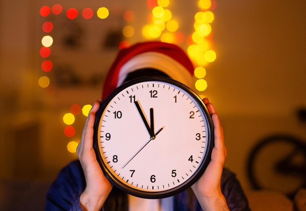 Contagem regressiva do conceito de ano novo. Homem com chapéu de Papai Noel mostrando o relógio