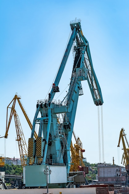 Containerfrachtfrachtschiff mit arbeitender Kranbrücke in der Werft am Tag.