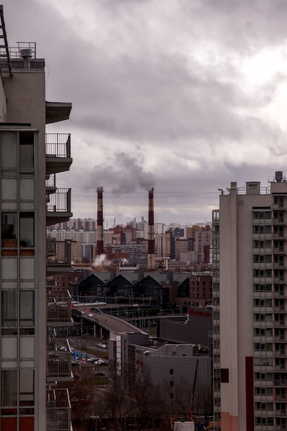 Contaminación ambiental y del aire, concepto de problemas ecológicos. El humo de las chimeneas de las fábricas contra un cielo nublado gris. Paisaje urbano.