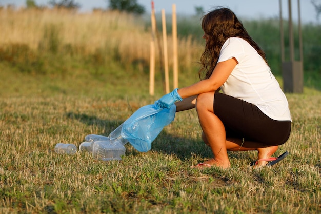 Contaminación plástica en el problema ambiental del mundo Una mano en un guante azul pone basura en una bolsa de plástico Retiro y limpieza de basura de territorios contaminados