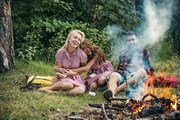 Contando piadas na fogueira Amigos rindo acampando na floresta Fumaça de fogueira cobrindo as pessoas