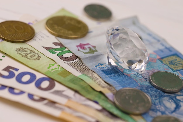 Contas de dinheiro ucranianas e diamantes fecham Grande quantidade de contas de hryvnia e grande gema perfeita na mesa Negócios e joias