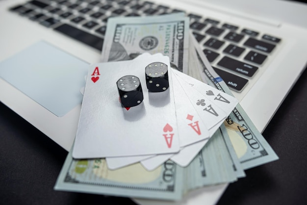 contas e dados de cassino e cartões de dólar no teclado do laptop isolado em fundo preto conceito de jogos de cartas de jogo