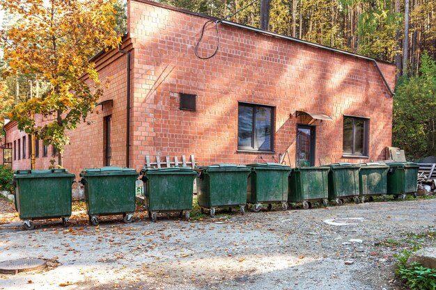Contêineres de lixo estão em fila perto de um edifício de tijolos cuidando do meio ambiente
