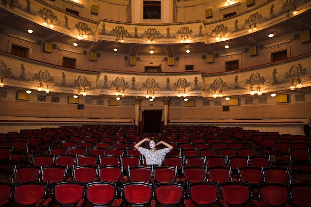 Contemplado artista mimo femenino sentado solo en un auditorio