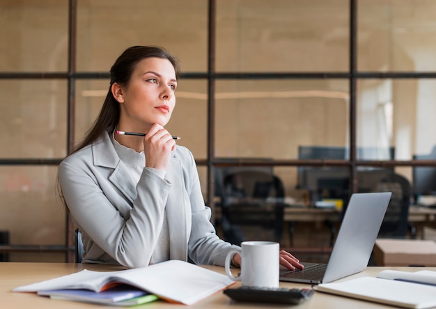 Contemplando a empresaria sentado frente a la computadora portátil en la oficina