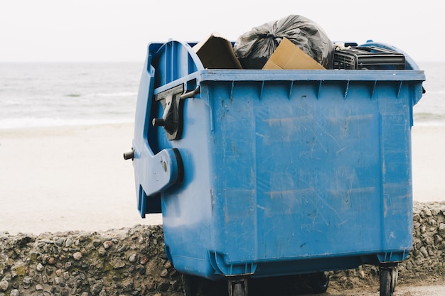 Contenedor de basura azul en la costa