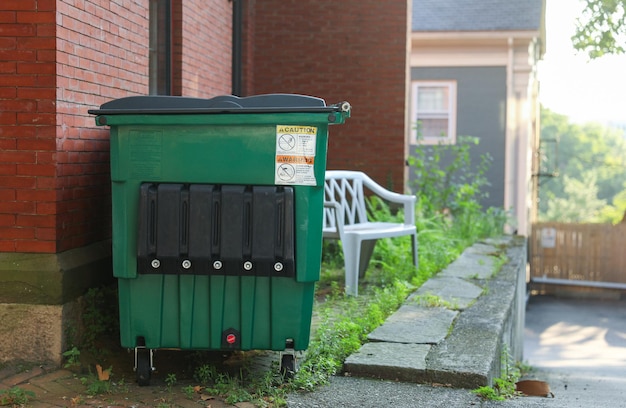 Un contenedor de basura verde con un letrero que dice "residuos".