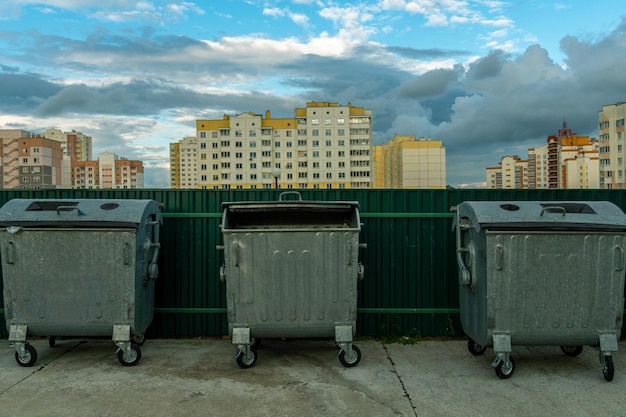 Foto contenedores de metal modernos para la recolección separada de basura botes de basura en la ciudad en el fondo de una casa problemas de desastres ambientales de recolección y eliminación de desechos en una gran ciudad