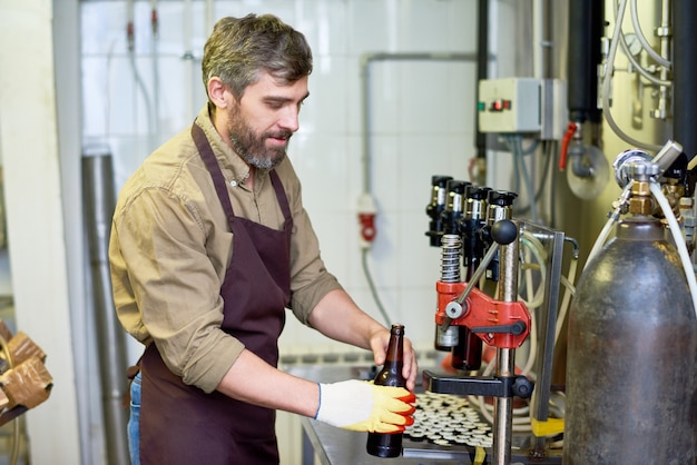 Contenido guapo técnico poniendo cerveza en botellas en fábrica