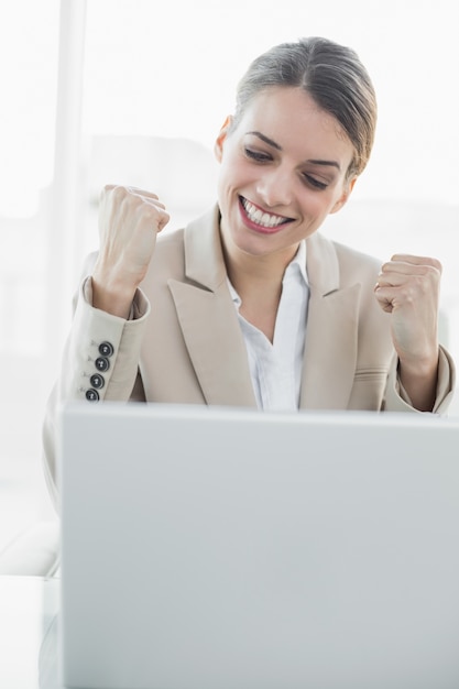 Contenido joven empresaria animando sentado en su escritorio