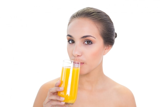 Contenido morena mujer bebiendo un vaso de jugo de naranja