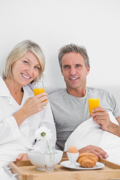 Conteúdo casal com suco de laranja no café da manhã na cama