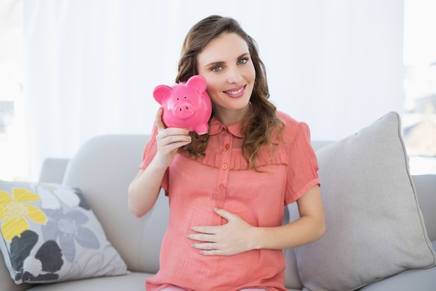 Conteúdo, mulher grávida, sacudindo, piggy bank, sentando, sofá