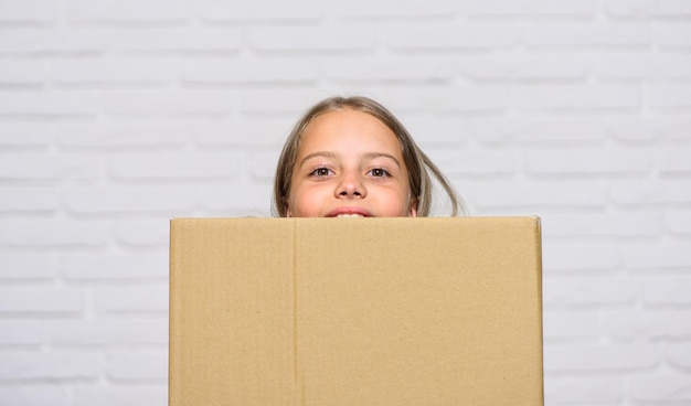 Continúe con una niña pequeña, una niña pequeña con una caja que se muda a un nuevo apartamento, la compra perfecta, el concepto de mudanza, se muda a una nueva casa, el concepto de alquiler, la reparación y la reubicación del espacio de copia de la infancia feliz.