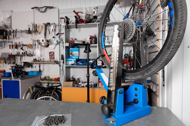 Contra o fundo da parede com ferramentas fechadas está um suporte de roda de bicicleta azul