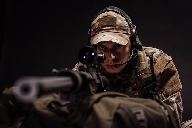 Contracto militar com seu rifle sniper na tecnologia de armas do exército de guerra noturna e conceito de pessoas