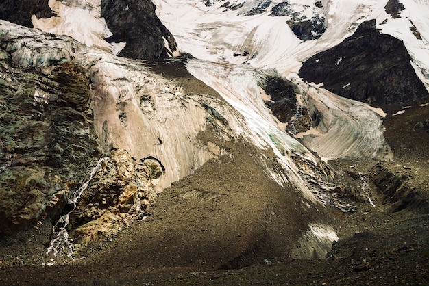 Contrafortes de geleiras gigantes. Incrível relevo rochoso com neve e gelo. Parede natural rochosa maravilhosa montanha enorme com pequenas cachoeiras. Água da geleira. Arte fantástica da natureza majestosa das montanhas.