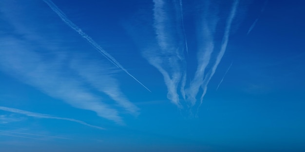 Contrail do avião contra o céu azul com nuvem branca Trilha de condensação do avião a jato Linhas de nuvens feitas de aeronaves