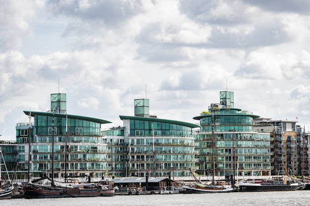 Contraste da arquitetura de vidro moderna e casas flutuantes antigas ancoradas no rio Tamisa, em Londres, Reino Unido.