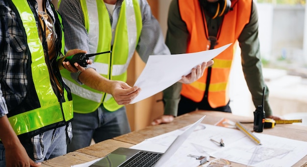 Contratista y arquitecto mirando el plan de la tableta portátil y hablando de trabajar en un gran proyecto de construcción en el interior del proceso de construcción