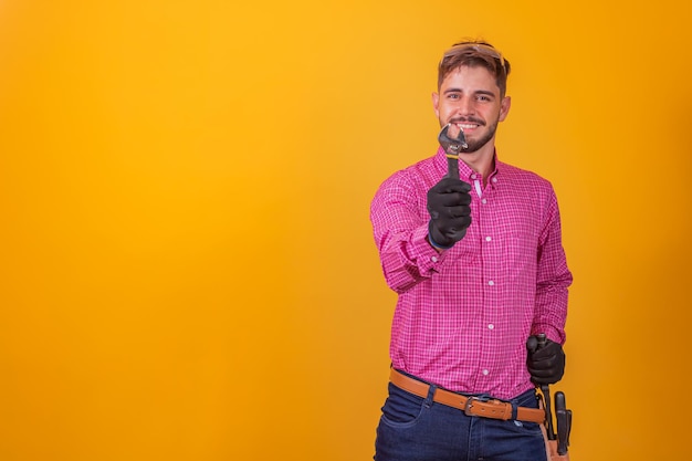 Contratista joven sosteniendo una llave sobre fondo amarillo. ingeniero, hombre, tenencia, el, reparación, llave